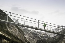 Low angle view of woman hiking on foot bridge, Holzgau, Tirol, Austria — стоковое фото
