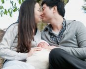 Parents kissing with sleeping baby — Stock Photo