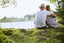 Rear view of couple sitting by lake — Stock Photo