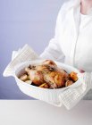 Woman holding dish of roast chicken — Stock Photo