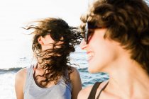 Сміються жінки в сонцезахисних окулярах на пляжі — стокове фото