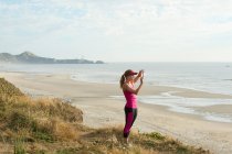 Активная молодая женщина фотографирует на пляже — стоковое фото