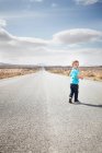 Мальчик ходит по асфальтированной сельской дороге — стоковое фото