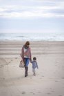 Mère et fille marchant sur la plage se tenant la main — Photo de stock