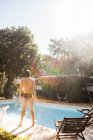 Вид ззаду людини, що стоїть на сонячному світлі біля басейну — стокове фото