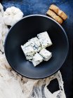 Bulbo de ajo y tazón de queso azul cúbico - foto de stock