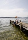 Uomo anziano seduto sul molo al lago — Foto stock