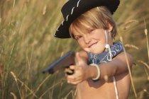 Портрет хлопчика в ковбойському капелюсі, що вказує на іграшковий пістолет — стокове фото