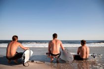 Три серфери на пляжі — стокове фото