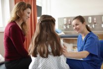 Жіноча медсестра, що розмовляє з пацієнтом дівчинка і мати — стокове фото