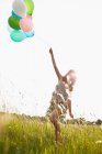 Frau mit Luftballons auf Feld unterwegs — Stockfoto