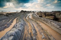 Вигнуті кам'яні утворення на пляжі — стокове фото