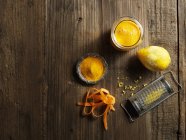 Top view of yellow raw juice with grated lemon and carrot on wood — Stock Photo