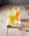 Стаканы свежего яблочного и апельсинового сока на сложенной салфетке — стоковое фото