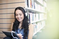 Young woman wearing headphones using digital tablet — Stock Photo