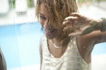 Mujer joven detrás de la ventana de la piscina del hotel, Río de Janeiro, Brasil - foto de stock
