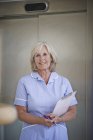 Portrait of mature female nurse in hospital corridor — Stock Photo