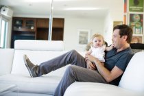 Baby girl sitting on father's lap — Stock Photo