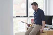 Man contemplating and reading papers by office window — Stock Photo
