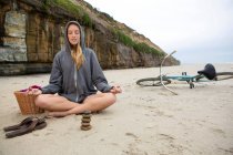 Frau meditiert mit Steinen am Strand — Stockfoto