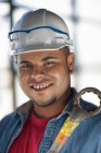Молодий будівельник носить твердий капелюх і тримає ключ, посміхаючись — стокове фото