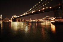 Manhattan buildings and bridge lit up at night — Stock Photo