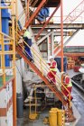 Рабочие поднимаются по лестнице на нефтяной вышке — стоковое фото