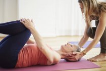 Mature female student lying on back holding knees in pilates class — Stock Photo