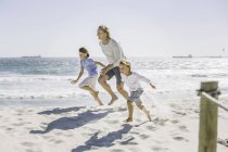 Отец и дети бегают по пляжу — стоковое фото