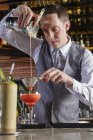 Caucasian Bartender pouring cocktail in bar — Stock Photo