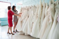 Mutter und Tochter schauen sich Brautkleider an — Stockfoto