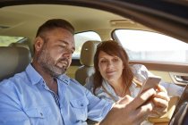 Couple en voiture, regardant smartphone — Photo de stock