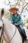 Lächelnder Junge reitet Pferd im Park — Stockfoto