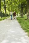 Старшая женщина и внучка прогуливаются по парку, используя трость — стоковое фото