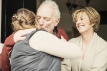 Father kissing adult daughter, mother smiling — Stock Photo