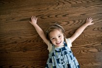 Bambina sdraiata sul pavimento in legno — Foto stock