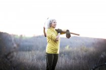 Reife Frau trägt Spitzhacke über der Schulter in der Landschaft — Stockfoto