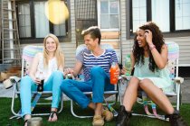 Three friends in deckchairs on roof — Stock Photo
