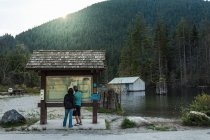 Pareja en la señal de información, Buntzen Lake, Columbia Británica, Canadá - foto de stock