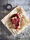 Raw rump steak on brown paper, top view — Stock Photo