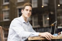 Fensterblick auf jungen Geschäftsmann mit Laptop in Café — Stockfoto