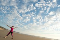Giovane donna sulla spiaggia con le braccia tese — Foto stock