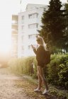 Молодая женщина на улице, ходит по улице, используя смартфон — стоковое фото