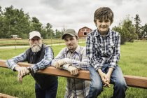 Multi generation family by fence on farm looking at camera smiling — Stock Photo