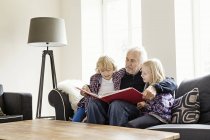Abuelo leyendo libro a los nietos - foto de stock