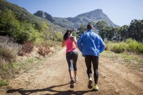 Giovane coppia jogging nella foresta — Foto stock