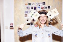 Mujer joven frente a la pared de fotos sosteniendo el signo de amor - foto de stock