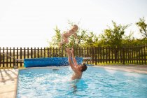Pai jogando filho no ar na piscina — Fotografia de Stock
