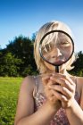 Girl playing with magnifying glass — Stock Photo