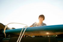 Adolescente desatando su tabla del techo del jeep - foto de stock